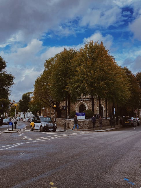 A city street scene in Grays with a mix of traditional and modern buildings lining each side of the road. In the foreground, a man wearing a blue shirt and black trousers is walking away from the came